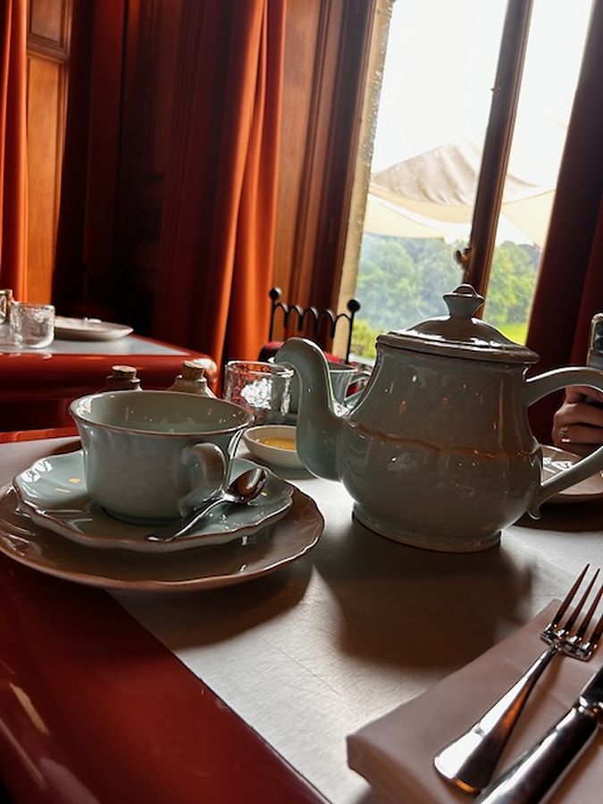 A ceramic teapot and cup on a linen-covered table in soft window light